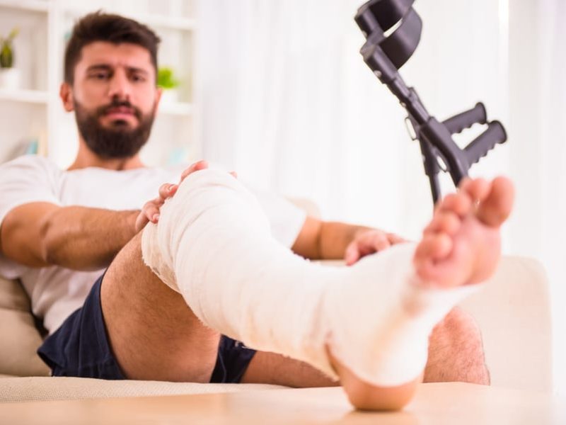 Portrait of a young man with injured leg at home