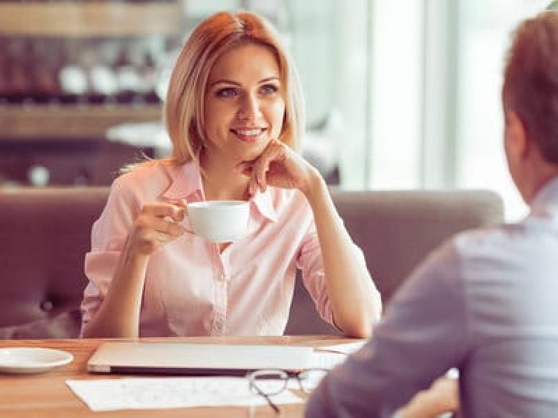 Beautiful business woman is drinking coffee talking and smiling while having a business meeting at the restaurant